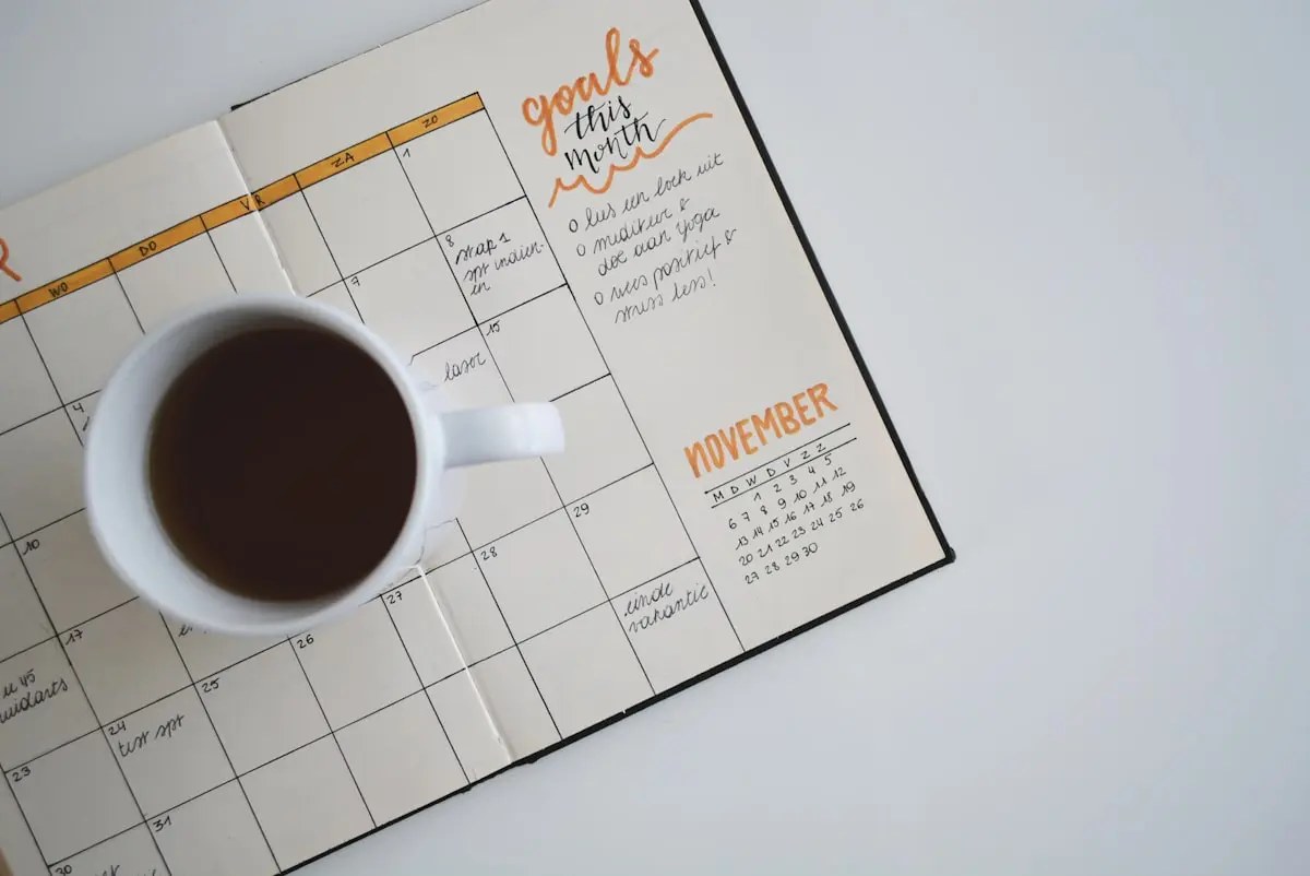 Open notebook and a cup of tea on a wooden table